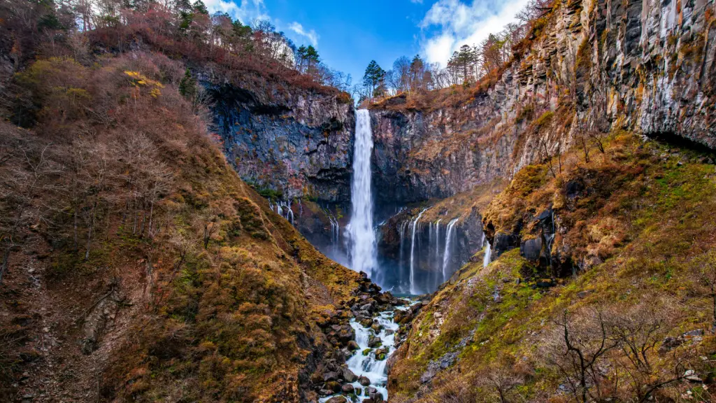 Kegon Waterfall in Nikko, Japan, cascading down a dramatic cliffside, surrounded by rugged autumn foliage and breathtaking natural scenery.