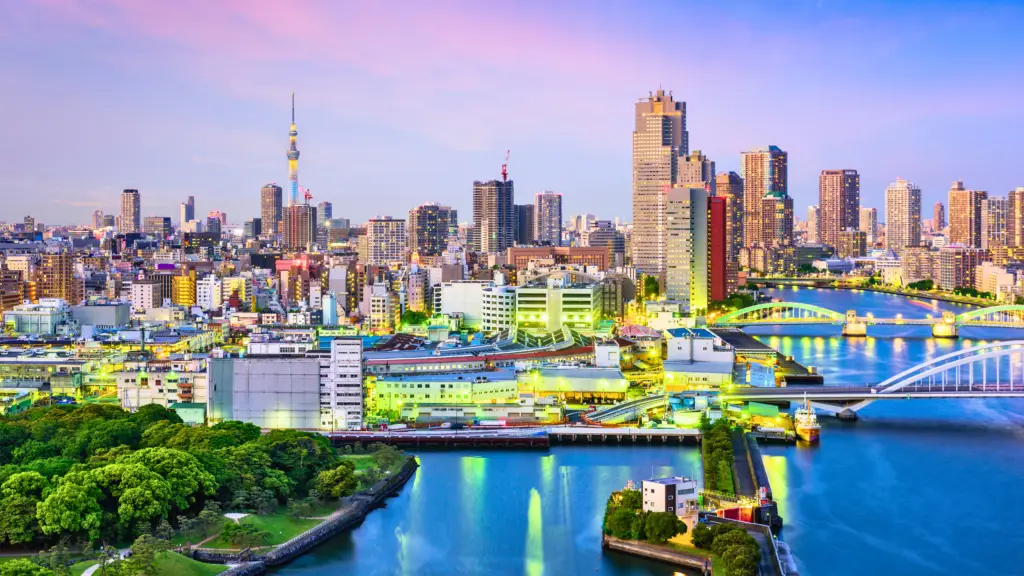 Scenic view of Tokyo skyline at dusk with the Sumida River, illuminated bridges, and Tokyo Skytree in the background.