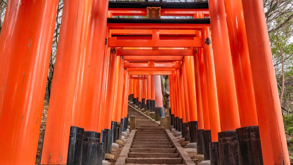 A mesmerizing path of vibrant vermilion torii gates at Fushimi Inari Taisha Shrine in Kyoto, Japan. The tunnel-like walkway leads up Mount Inari, creating one of Kyoto’s most iconic and photogenic landmarks.