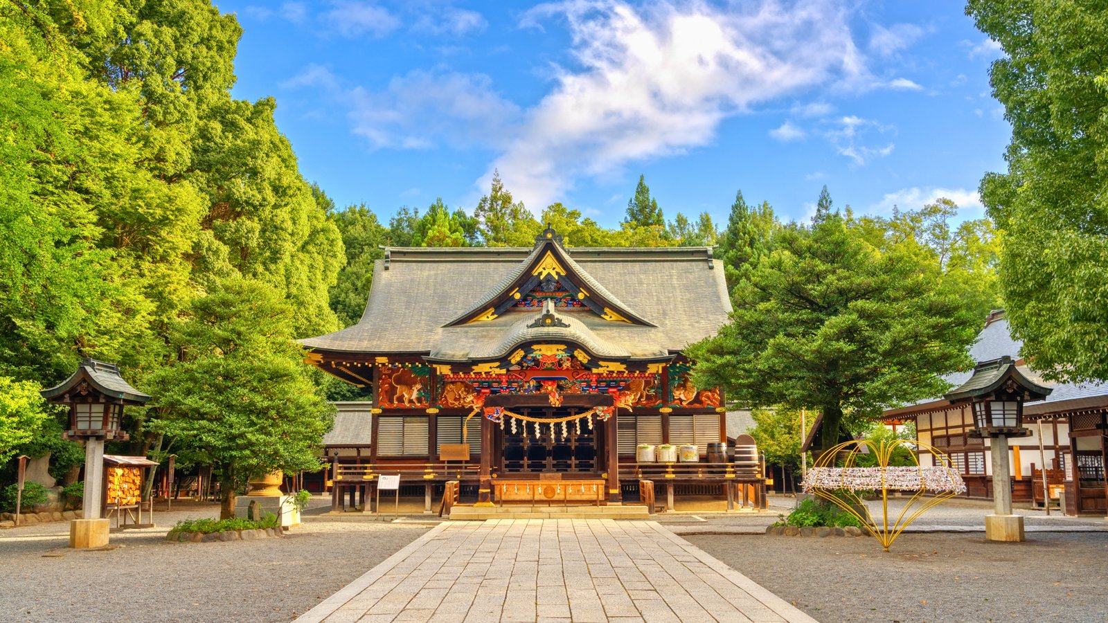 Chichibu Shrine in Chichibu, Japan The historic Chichibu Shrine in Chichibu, Japan, surrounded by lush greenery, featuring intricate wooden carvings and a peaceful courtyard under a bright blue sky.