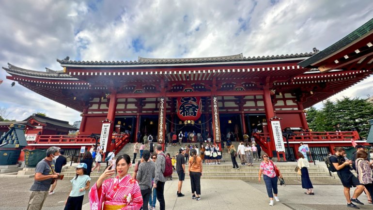 Tourists and locals at Senso-ji Temple in Tokyo, Japan, a historic Buddhist temple known for its vibrant red architecture, large lantern, and cultural significance.