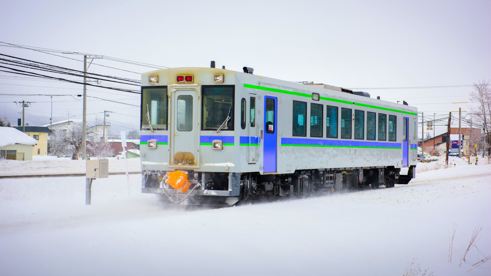 Train car passing through Asahikawa in Hokkaido, Japan A local train passing through the snowy landscape of Asahikawa, Hokkaido, Japan, with a bright winter backdrop, making its way through the frosty scenery.